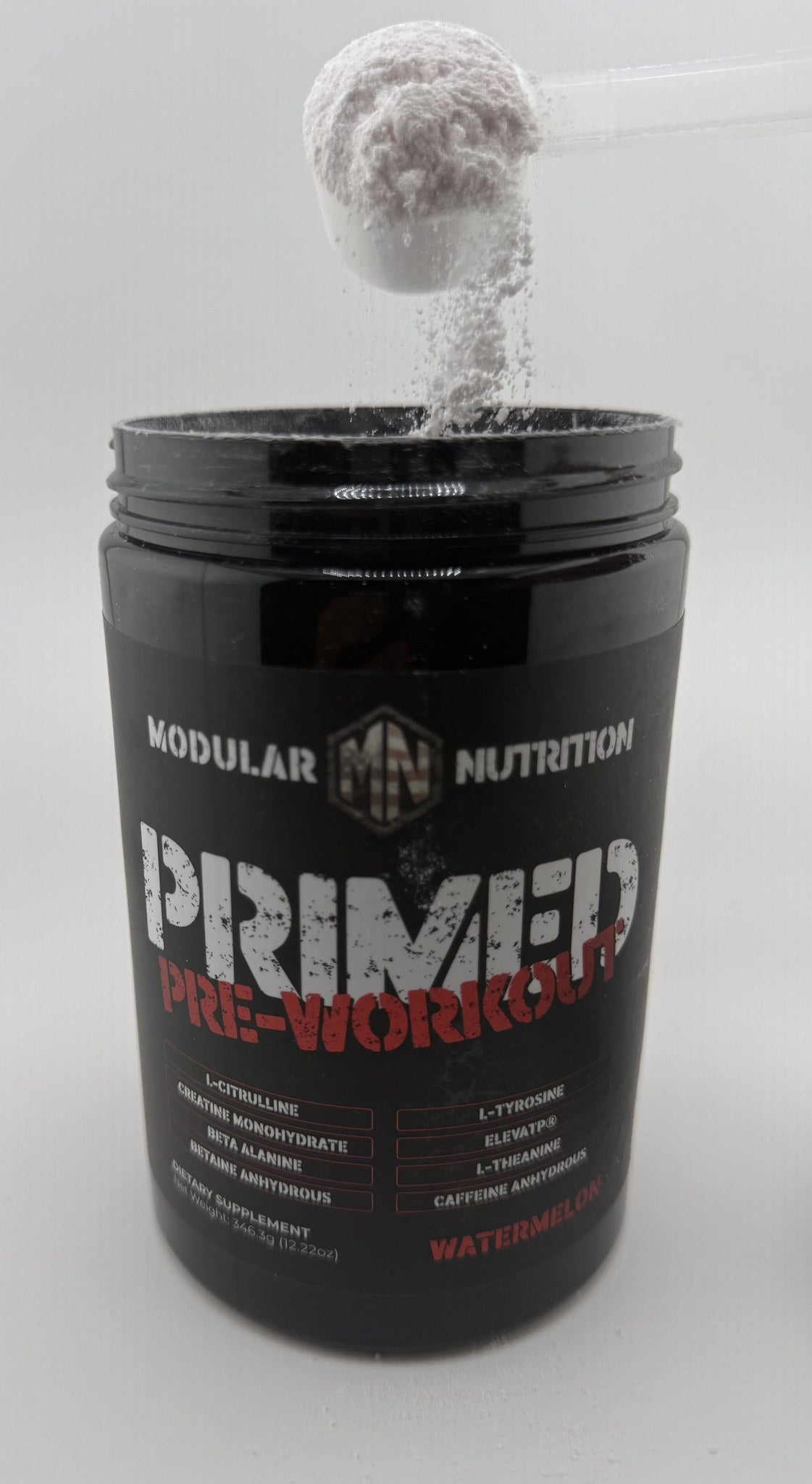 Scoop pouring pink Primed Pre-Workout powder into the open jar